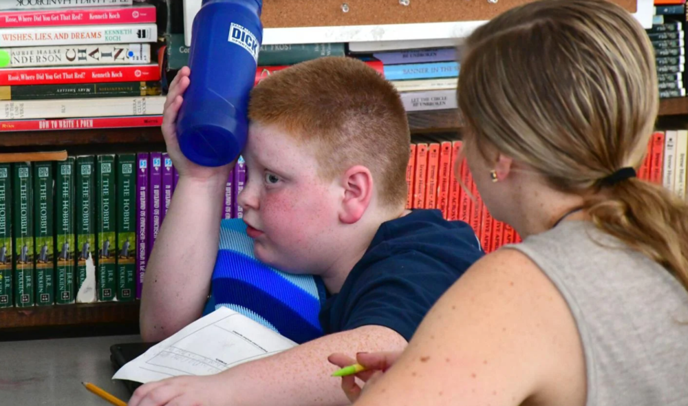 Lyam Lefebvre, 11, cools his forehead with his water bottle in his sixth grade class with Mike Little on Wednesday at Clarksburg Elementary School. With no air conditioning in the majority of the building, classes will be dismissed early on Thursday because of the unseasonable heat